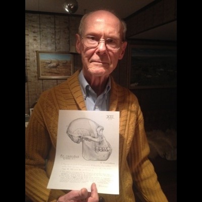 Ray's portrait of Jay in his studio with a drawing of the skull of Ardipithecus an early hominin.