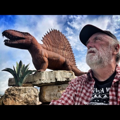 Ray striking a dramatic pose in front of a life size metal Dimetrodon sculpture in front of the Whiteside Museum.